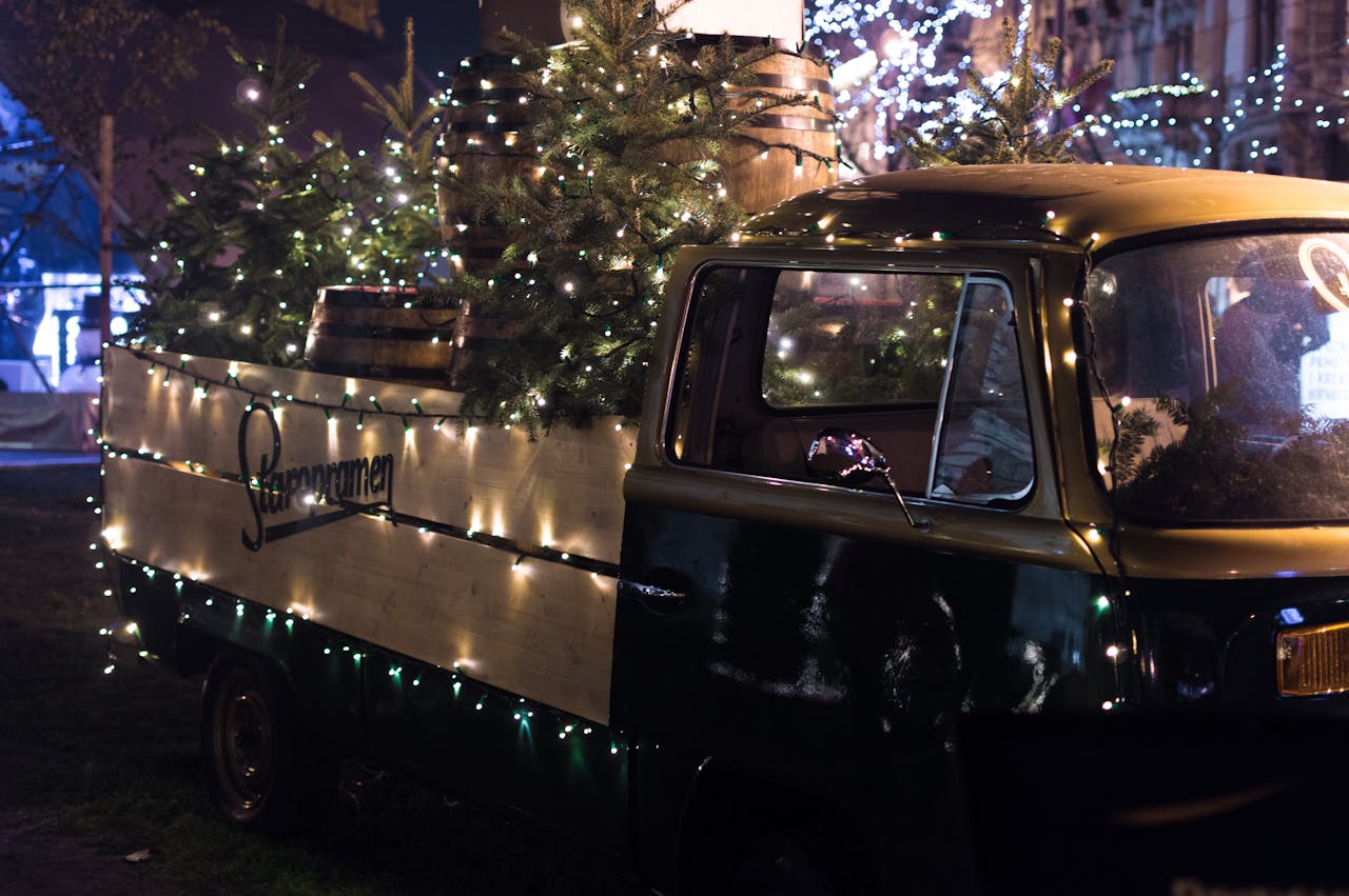 Services-03 A vintage truck adorned with Christmas lights and trees, creating a festive atmosphere at night.